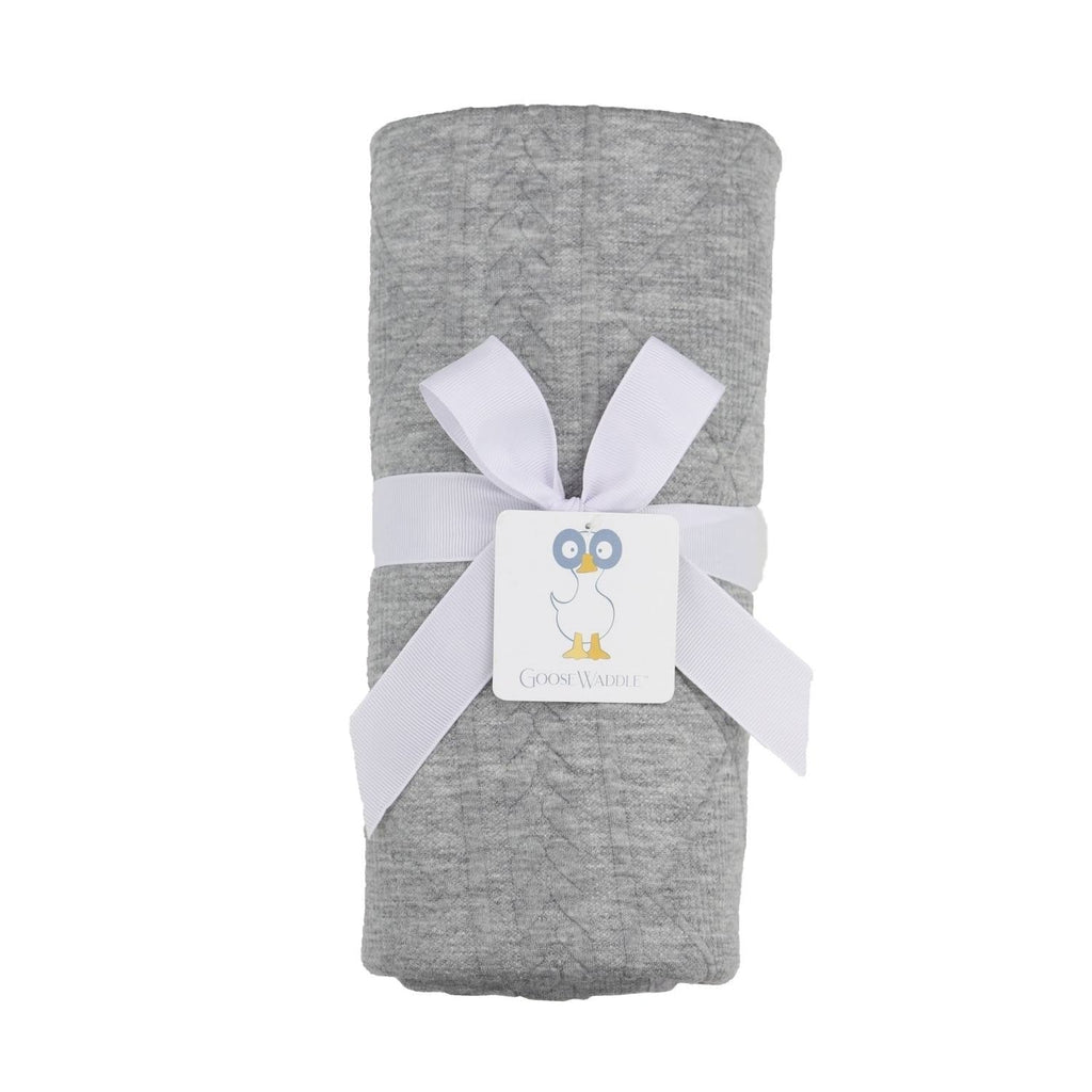 Gray Knit Blanket by Goosewaddle® neatly rolled and tied with a white ribbon, perfect for adding warmth and style to a baby's nursery.