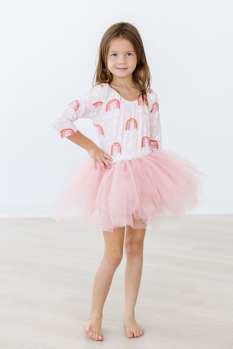 Another view of a young girl in the Fun & Flowers 3/4 Tutu Leotard, displaying the layered pink tutu as she poses confidently with her hands on her waist.