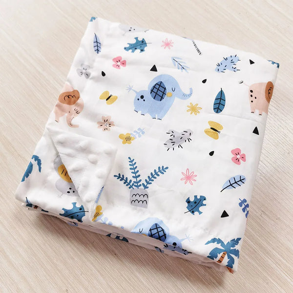 Folded white two-sided children's minky blanket with blue elephant, palm trees and colorful prints; raised dot texture.
