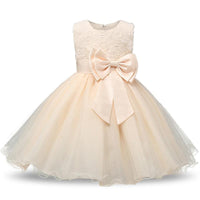 Champagne tulle special occasion dress for girls with lace bodice, glittery skirt, and large satin bow at the waist.