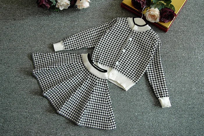 Flat lay of the Sacha Marie Knitted Girls Houndstooth Skirt Set in black, highlighting the chic cardigan and flared skirt design for little girls.