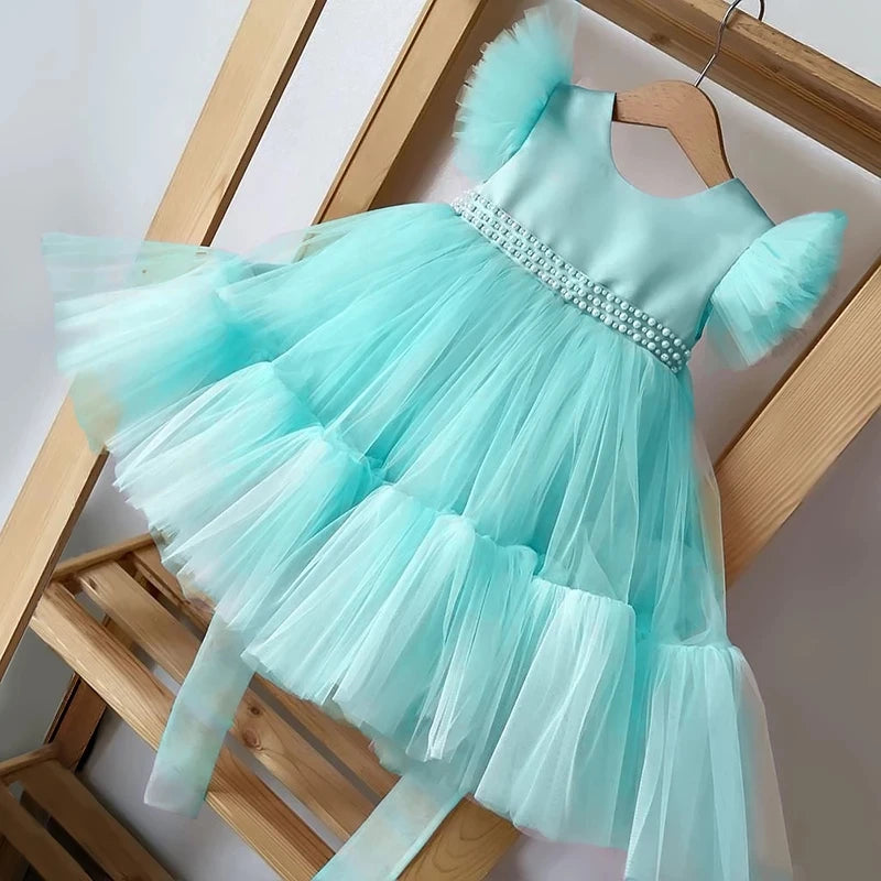 Pretty In Tulle Girls Tulle Party Dress in mint green hanging on a wooden rack, showcasing decorative beaded waist and voluminous tulle skirt.
