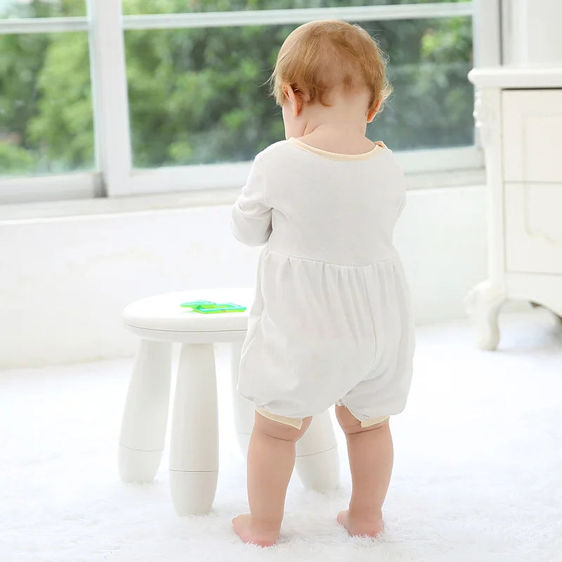 Back view of a toddler wearing a white special occasion romper with button-back closure, suitable for formal events.