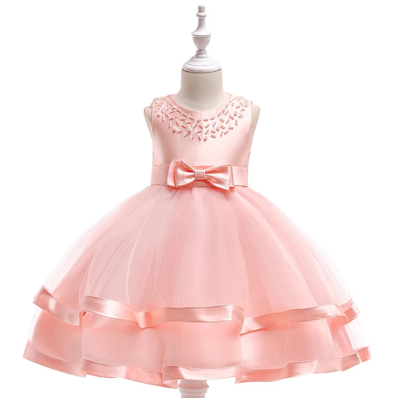 The 'Sacha Marie' Elegant Tiered Special Occasion Dress in soft pink, featuring a delicate tiered skirt and a decorative bow, perfect for special occasions.
