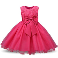 Pink girls' special occasion dress with floral lace bodice, large satin bow, and sparkling tulle skirt.