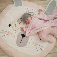 Baby sleeping on a pink bunny-shaped mat with a book next to it