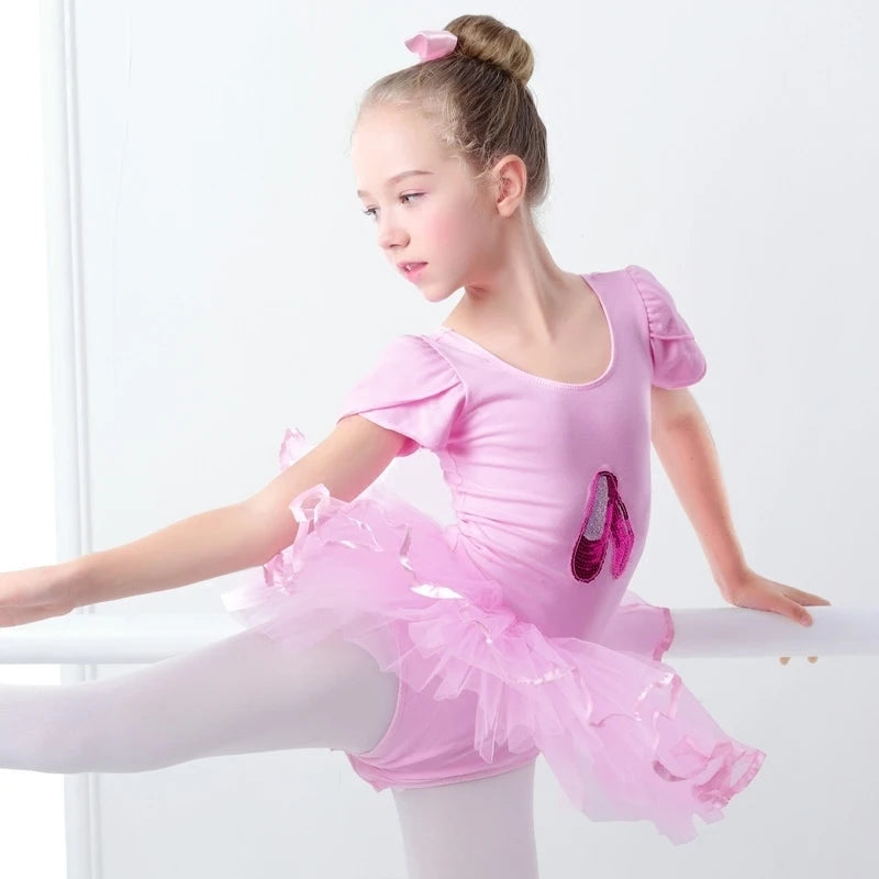 A young dancer practicing in the 'Poppy' Pink Sequined Slipper Chiffon Tutu Dress, showcasing elegance with a layered chiffon skirt and satin trim.