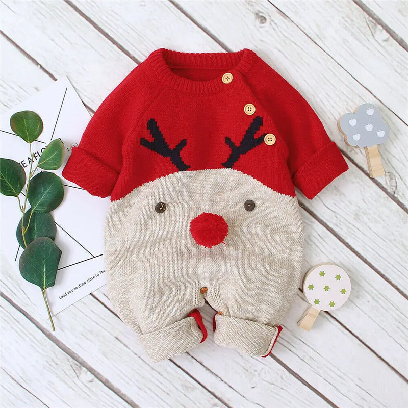 Rudy Reindeer Knit Children's Winter Romper in red and beige, styled with decorative props on a wooden background.