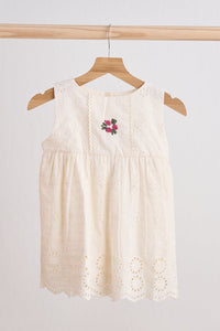 Beige sleeveless dress with floral embroidery on a wooden hanger against a white background