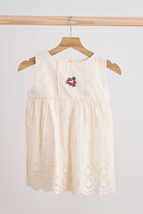 Girls white hand-embroidered lace dress with pink floral embroidery on hanger.