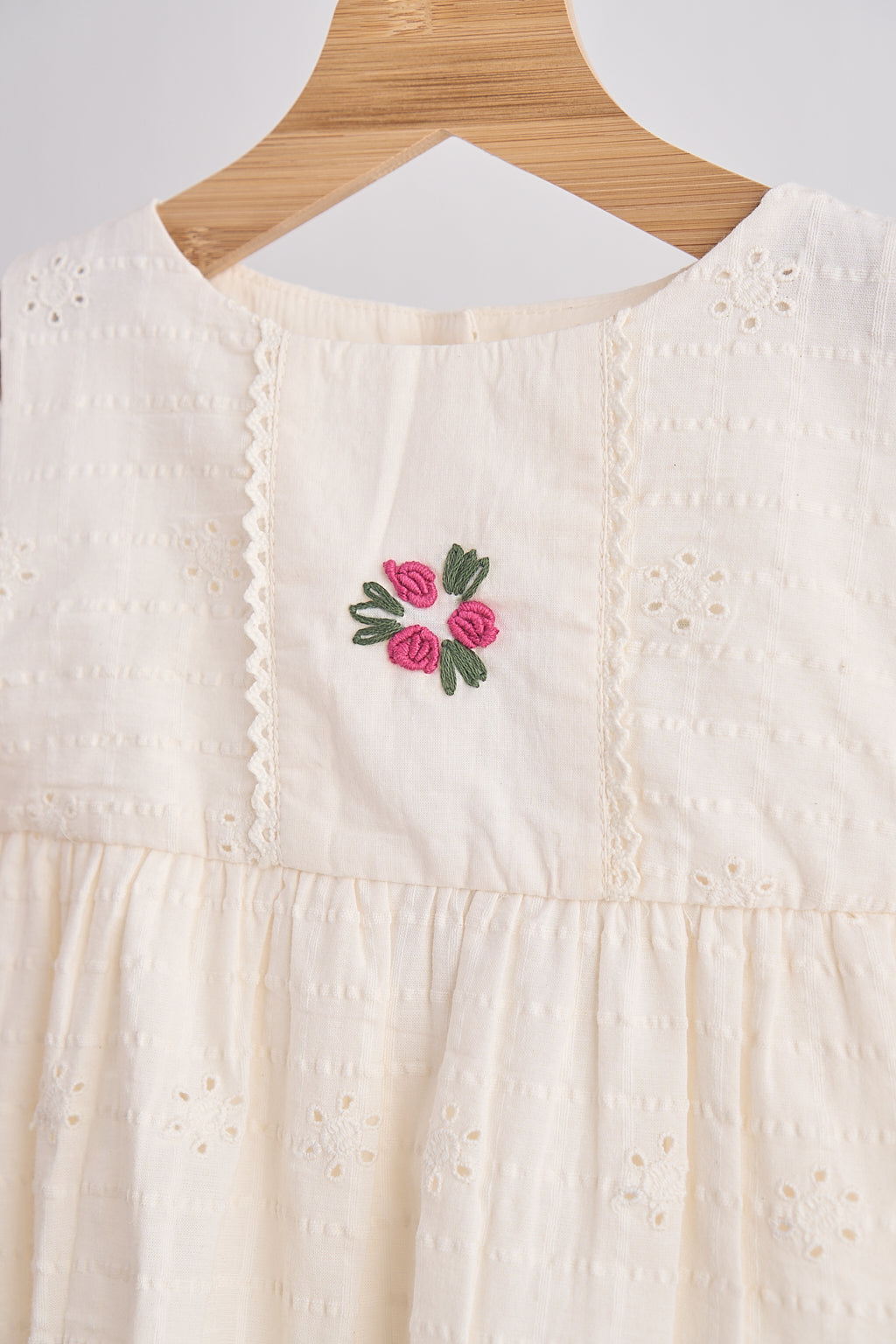 White dress with floral embroidery on a wooden hanger
