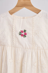 White dress with floral embroidery on a wooden hanger