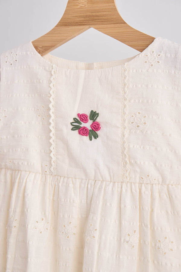 Girls white hand-embroidered cotton lace dress with pink floral embroidery on the bodice and delicate eyelet details.