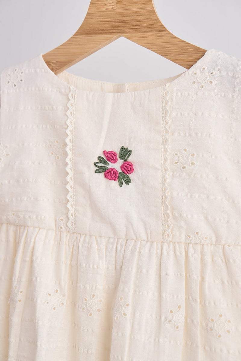 Girls white hand-embroidered cotton lace dress with pink floral embroidery on the bodice and delicate eyelet details.