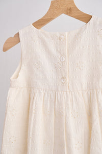 White sleeveless dress on a wooden hanger against a light gray background