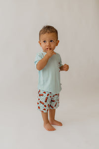 Toddler in light blue bamboo lounge set with red fire truck print shorts against white background