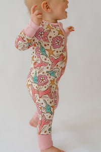 Side view of baby in stretchy bamboo sleeper showing full pink zipper line and convertible foot design