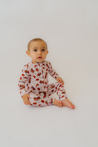 Baby in pink fire truck onesie with red trucks and black stars on white background