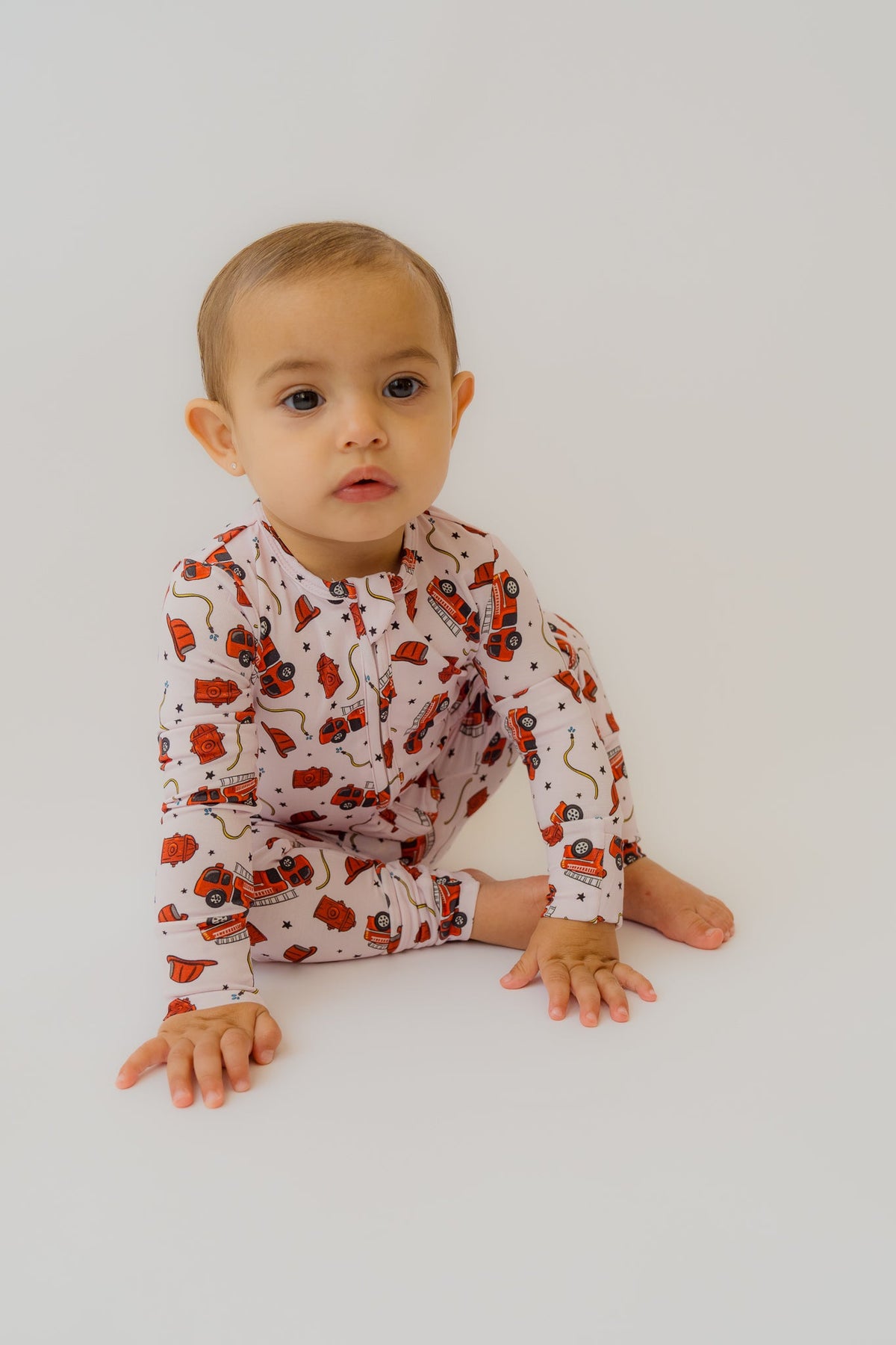 Close-up of crawling baby in soft pink bamboo onesie showing detailed fire truck print