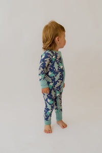 Toddler in Sharks Loveralls bamboo convertible onesie with teal cuffs and shark-print pattern.