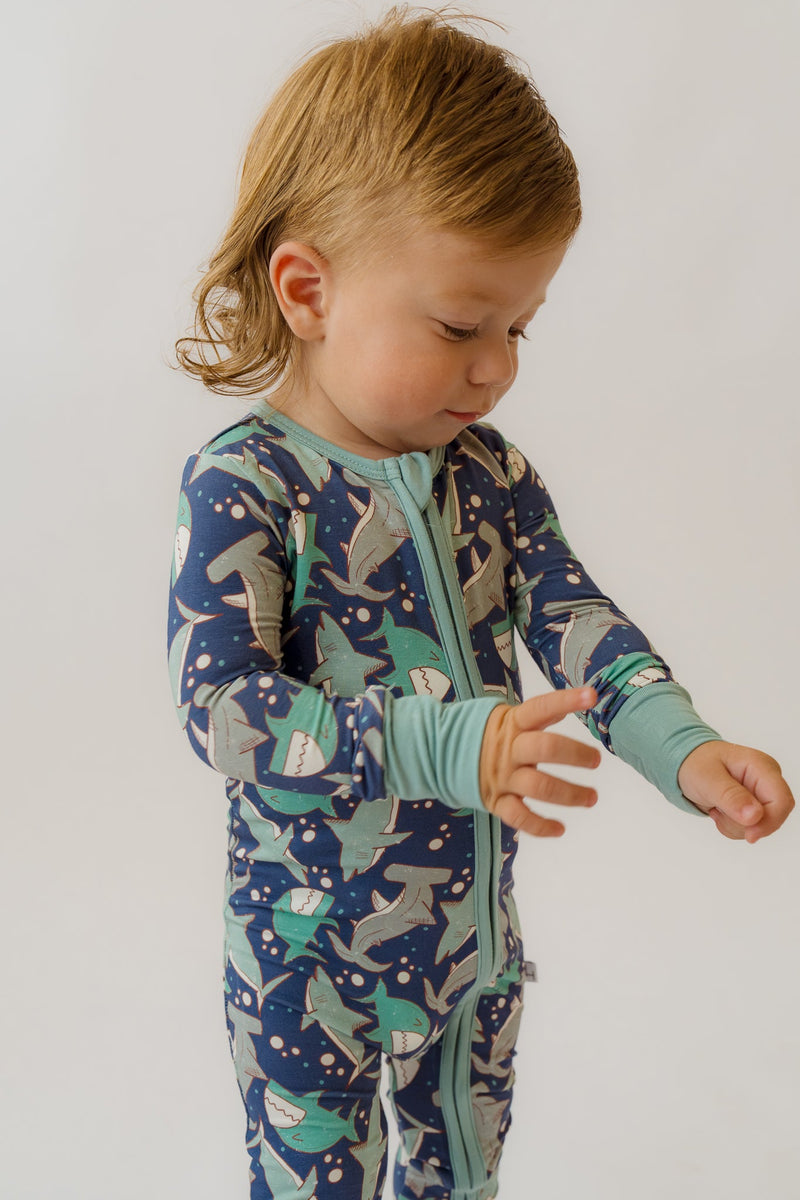 Toddler wearing shark print convertible bamboo loveralls with front zipper, featuring soft stretchy fabric for cozy sleep and play.