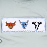 Embroidered patch with three cow faces on a light gray background