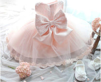Pink tulle special occasion dress for girls with lace back bow and white Mary Jane shoes.