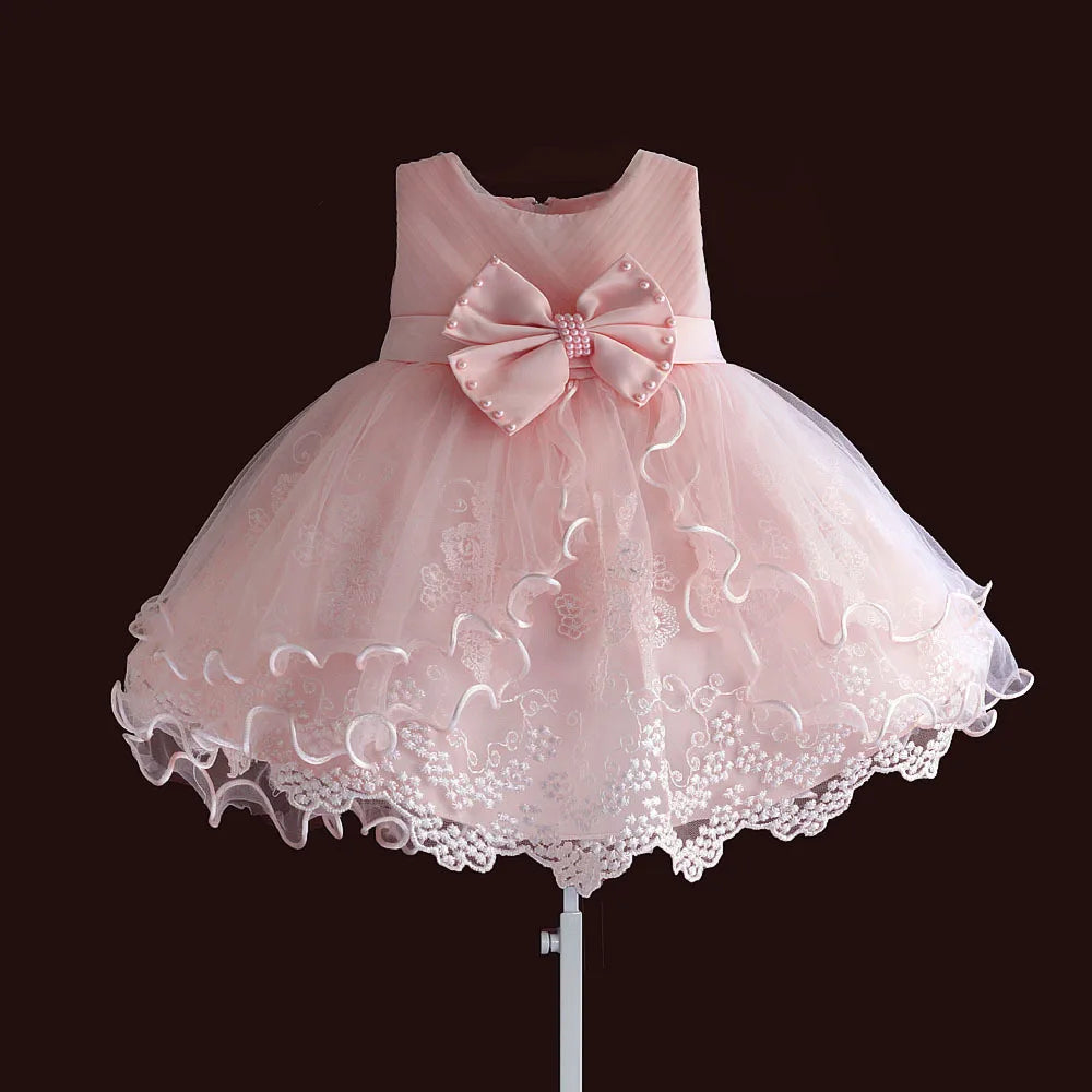 Aurora Elegant Pearl Bow newborn dress in pink with beaded bow and lace-tulle hem.
