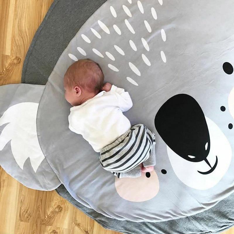 Baby lying on a large circular mat with cartoon designs on a wooden floor.