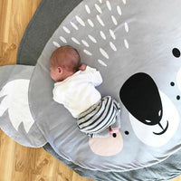 Baby lying on a large circular mat with cartoon designs on a wooden floor.