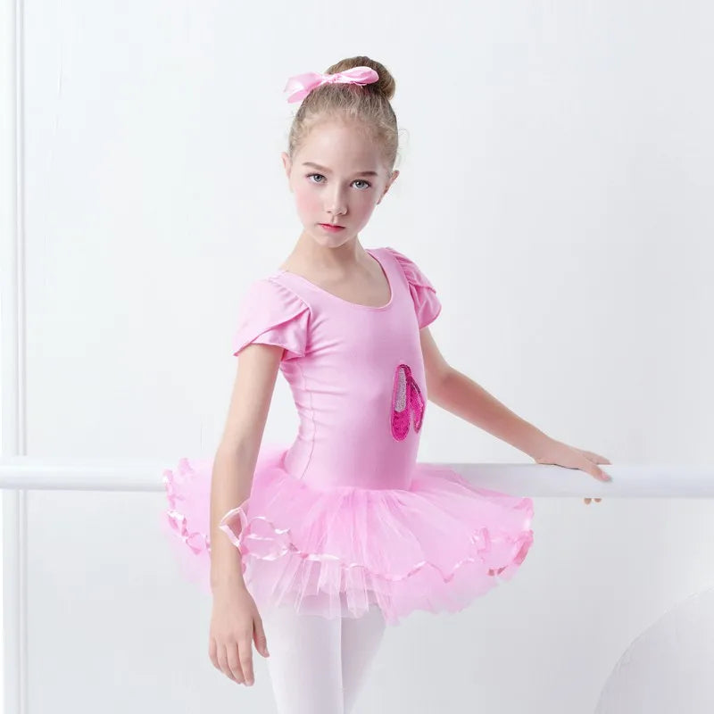 A dancer poses gracefully in the 'Poppy' Pink Sequined Slipper Chiffon Tutu Dress, featuring sparkly ballet slippers and a beautiful layered skirt.