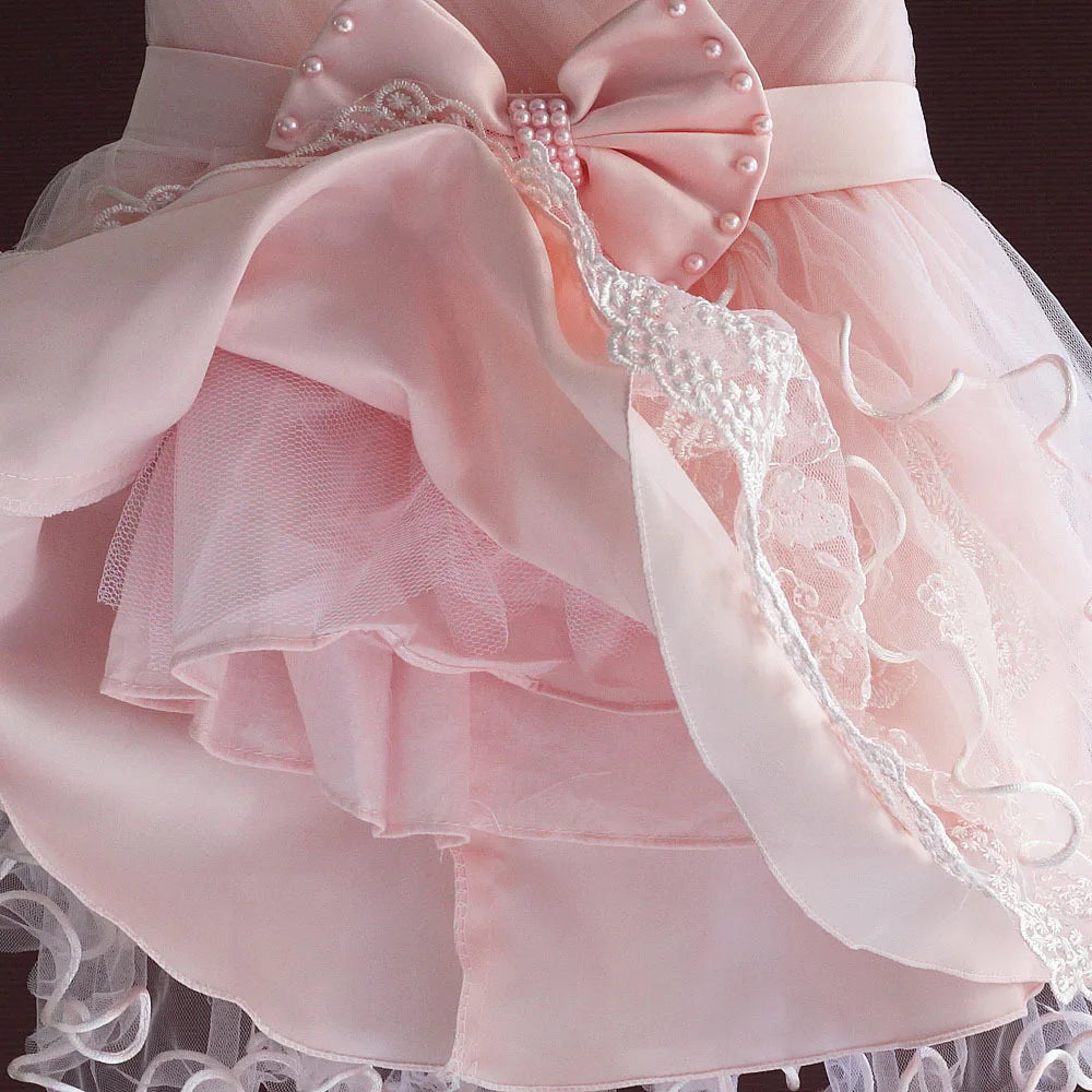 Pink baby dress with large pearl-beaded bow, lace trim, satin layers for newborn to 3 months.