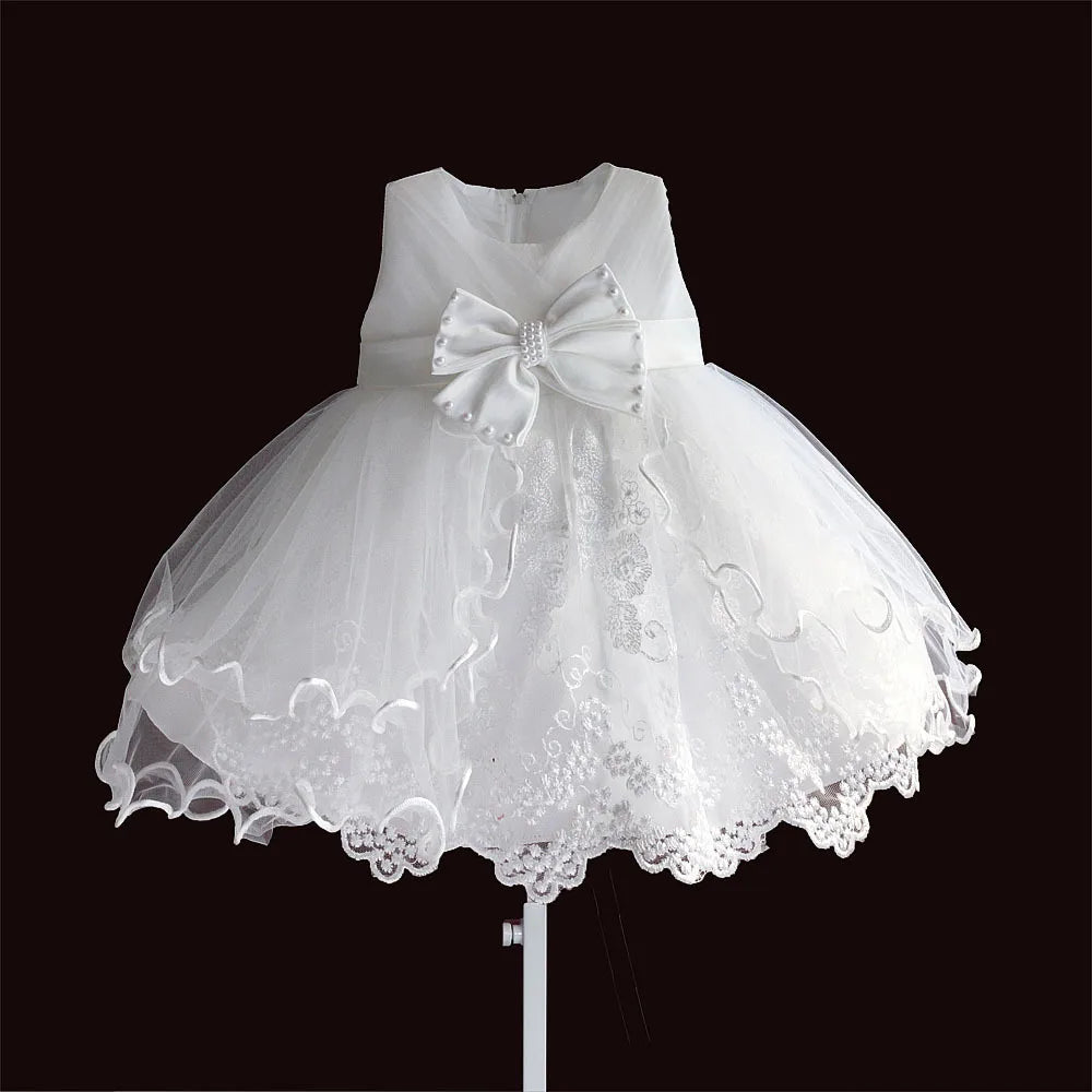 White baby dress for 0-3 months with large satin bow, pearl accents, and lace-trimmed tulle skirt.
