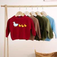 Five colorful embroidered duck sweaters hanging on wooden rack in red mocha green and blue shades