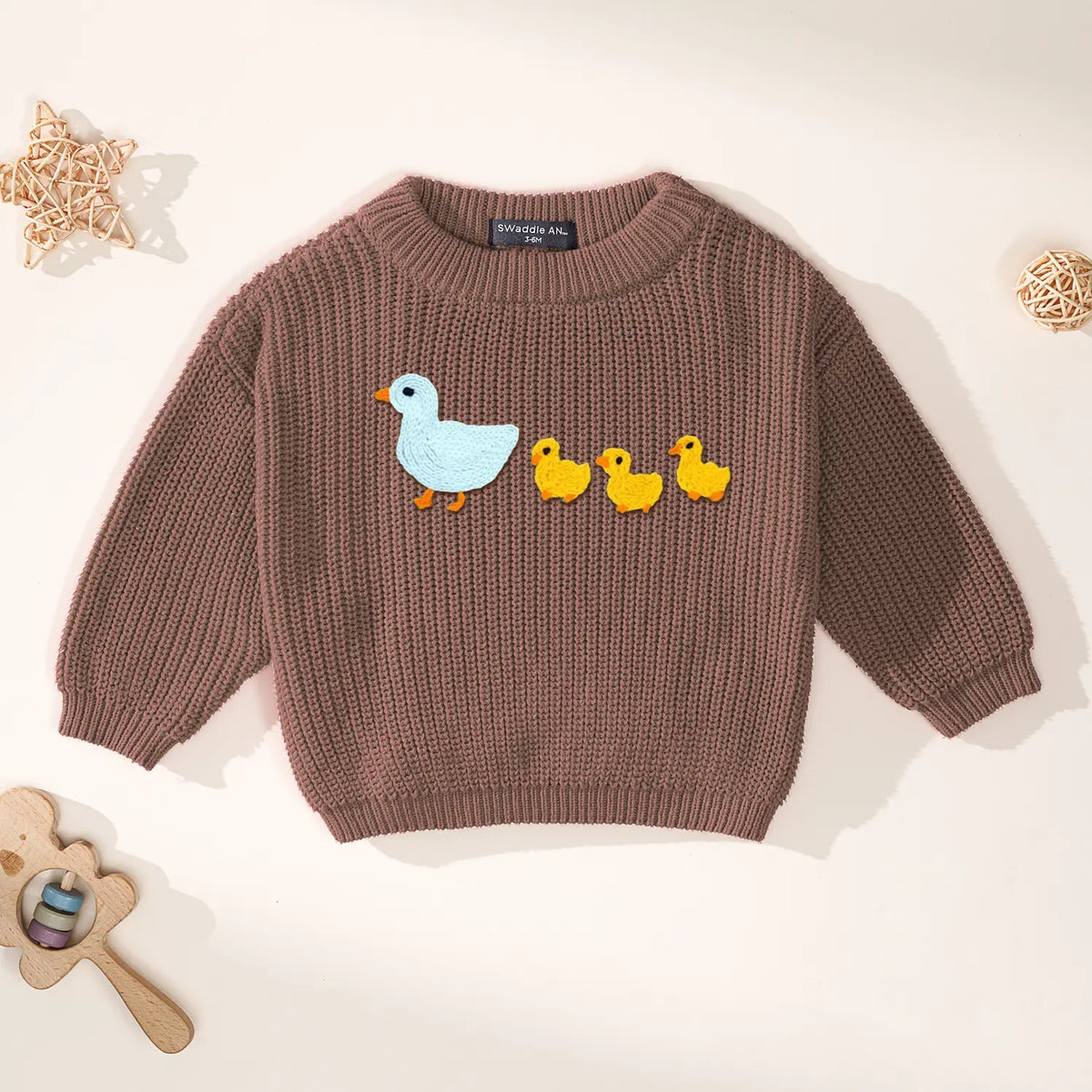 Mocha brown baby sweater with blue mother and yellow chicks embroidery against white background