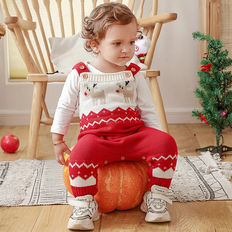 Adorable Reindeer Winter Cutie Baby Knit Romper Overalls displayed on a child sitting on a pumpkin, showcasing the festive red design with reindeer.