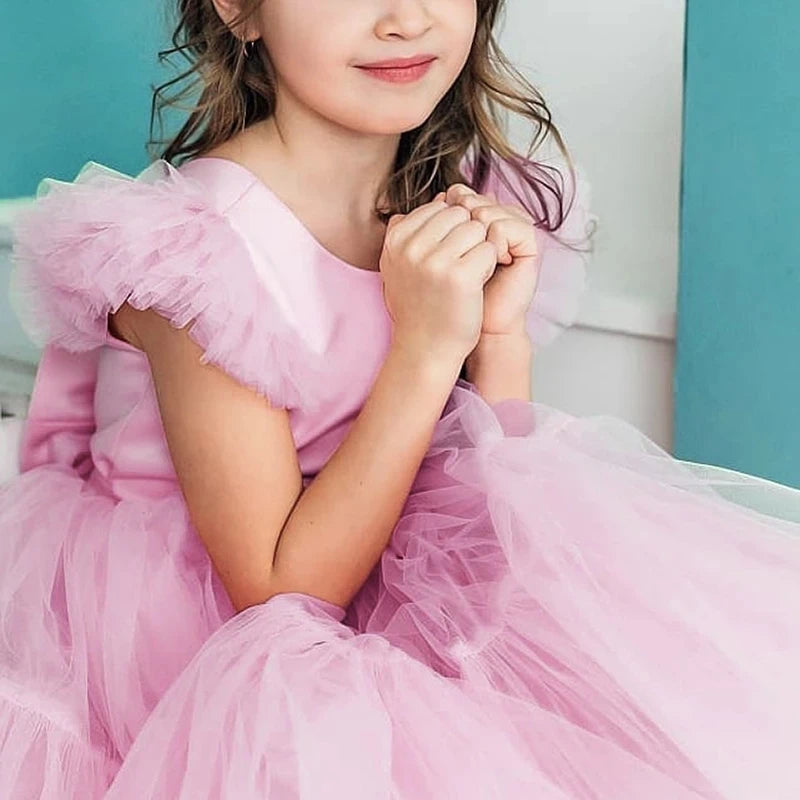 Close-up of a young girl in the 'Pretty In Tulle' Girls Tulle Party Dress, featuring stylish fly-away sleeves in pink tulle.