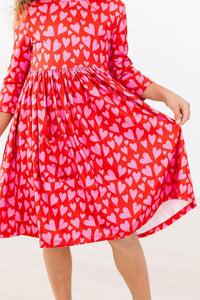 Red 3/4 sleeve twirl dress with pink hearts, front pocket, and full skirt for school or play.