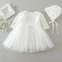 White lace baby dress with matching bonnet on a gray background