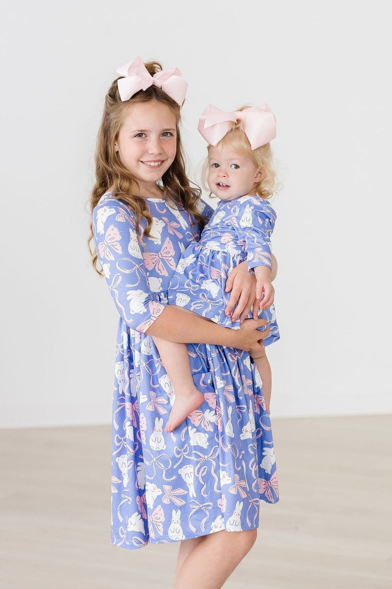 Two girls wearing the Hop, Skip & Twirl 3/4 Sleeve Pocket Twirl Dress, one in a larger size and the other in a matching dress, capturing a moment of joy.