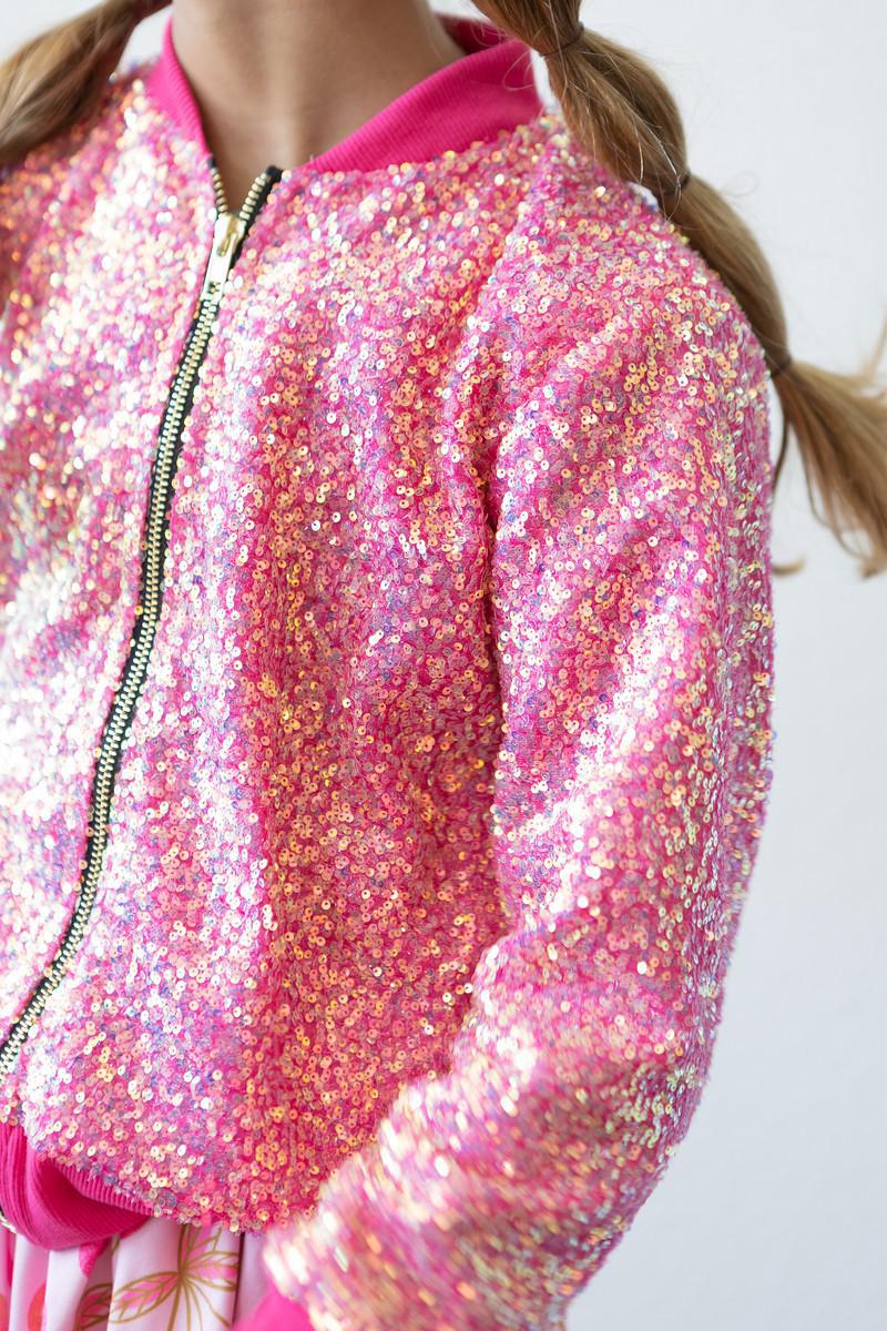 Child showcasing the Hot Pink Sequin Jacket by Mila & Rose, shimmering with vibrant sequins and a playful zipper, perfect for adding sparkle to any outfit.