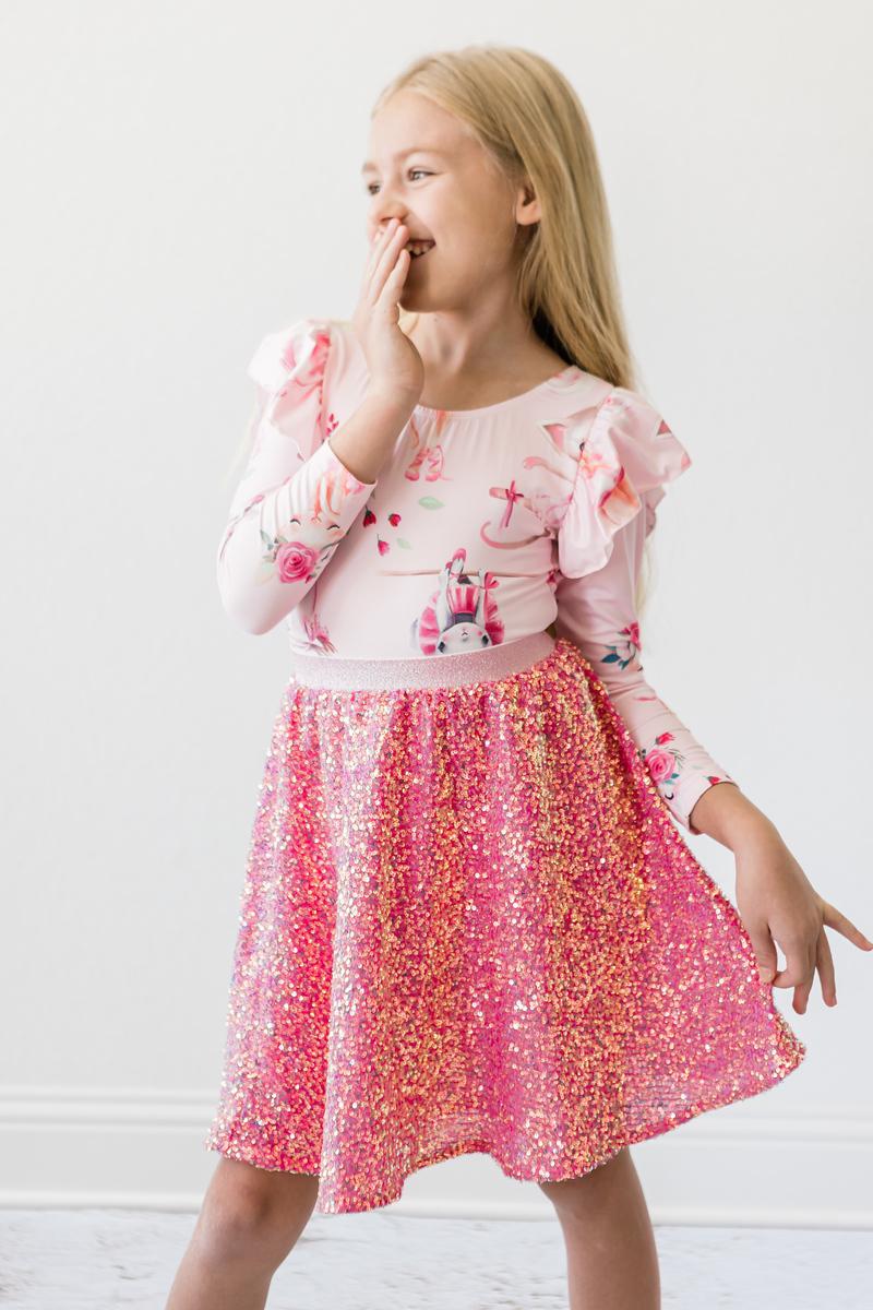 Charming young girl joyfully posing in her Hot Pink Sequin Twirl Skort from Mila & Rose, capturing the sparkle of sequins and the joy of childhood fashion.