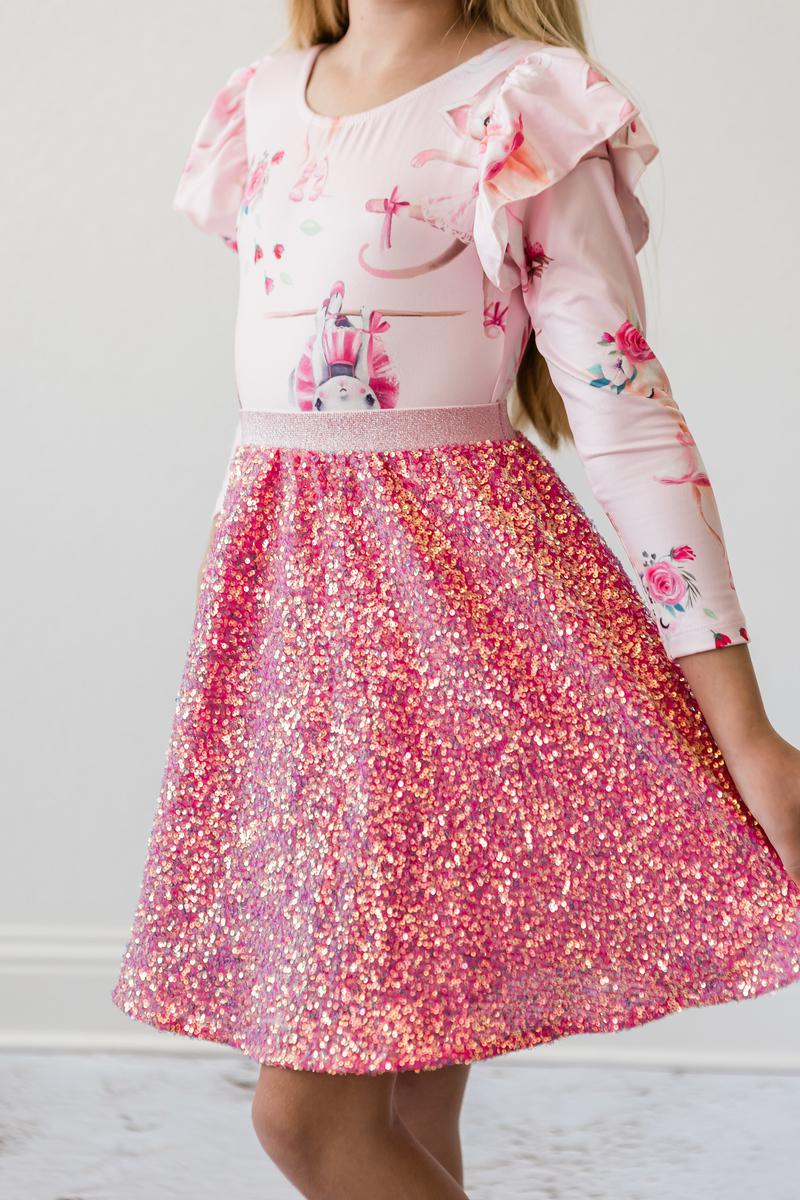Beautiful young girl elegantly displaying the side view of her Hot Pink Sequin Twirl Skort from Mila & Rose, highlighting the shimmering sequins and playful silhouette.