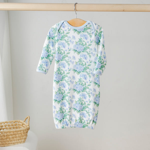 Hydrangea Heaven organic cotton kids pajama set with blue hydrangea print, hanging on a wooden rod.