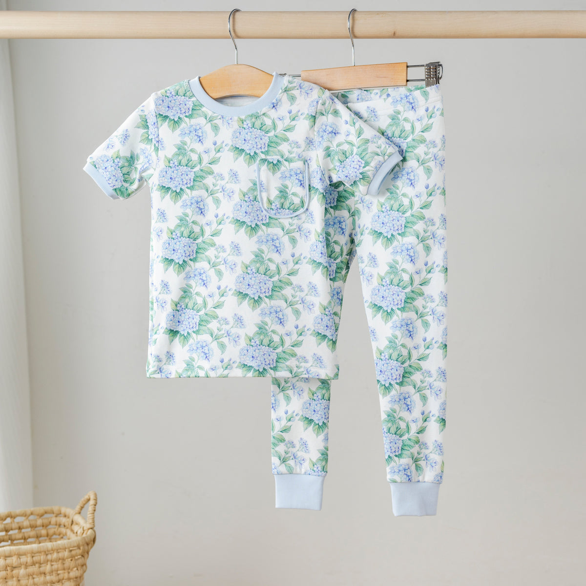 Blue hydrangea print organic cotton kids pajama set with light blue trim, featuring a short-sleeve top with pocket and matching pants.