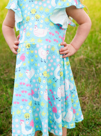 A young girl smiling while wearing the Aqua Spring Chicken Floral Farm Print Dress, showcasing its versatility for casual wear.