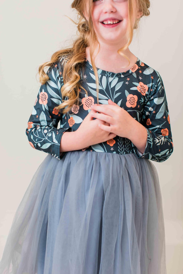 Girl wearing a floral long sleeve tutu dress in "Into the Night" print with a grey tulle skirt. Perfect for dressing up or play.