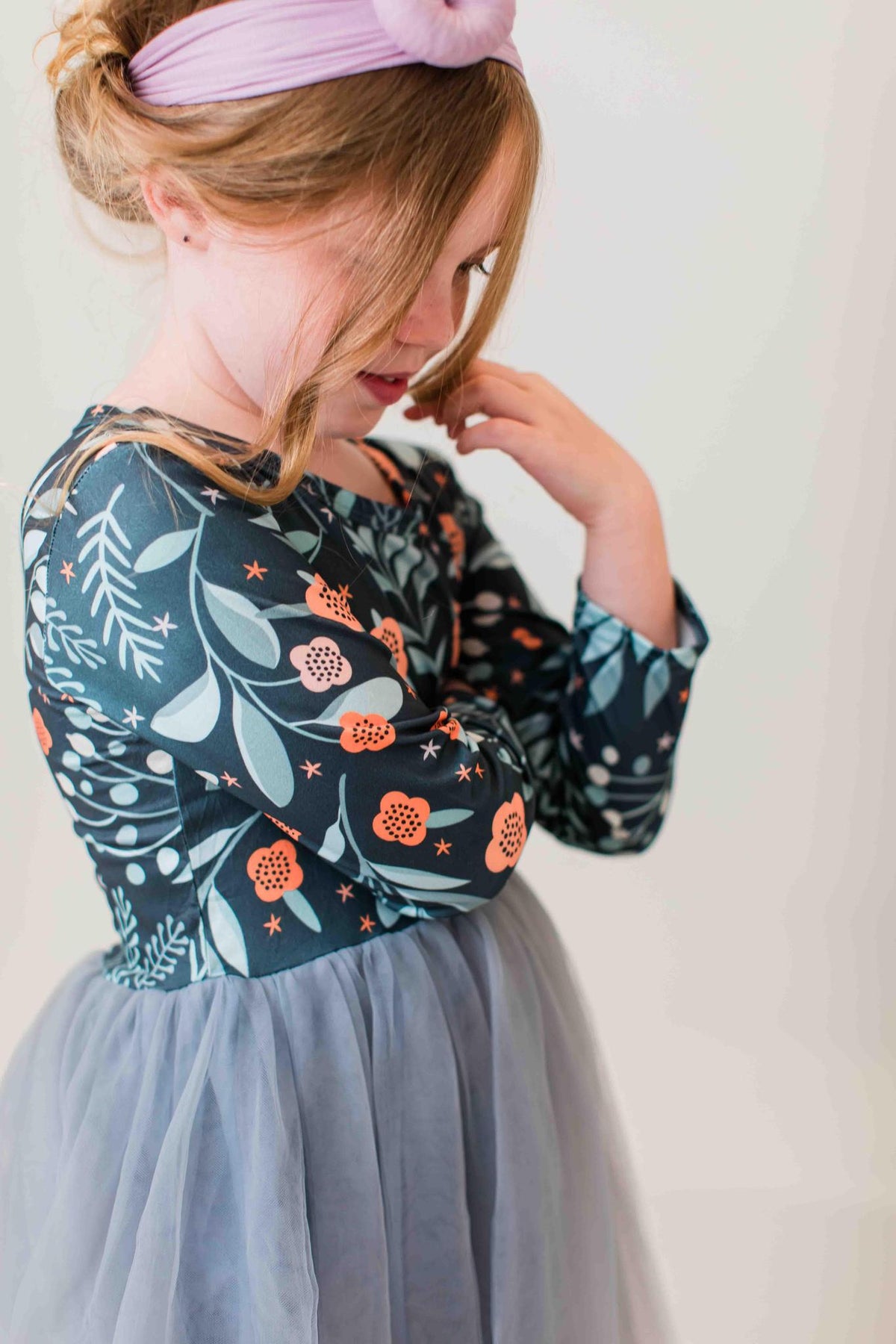 Girl wearing Into the Night long sleeve tutu dress with floral bodice and grey tulle skirt, styled with a pink headband.