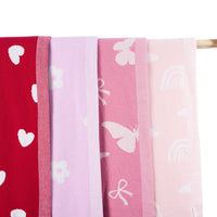 Four folded blankets hanging vertically on wooden rod, showing color gradient from red hearts to lavender daisies with ribbed