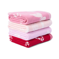Stack of four neatly folded jacquard knit blankets in pink butterflies, pale rainbows, lavender daisies, and red hearts on